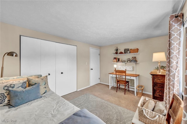 bedroom with a closet, light carpet, and a textured ceiling