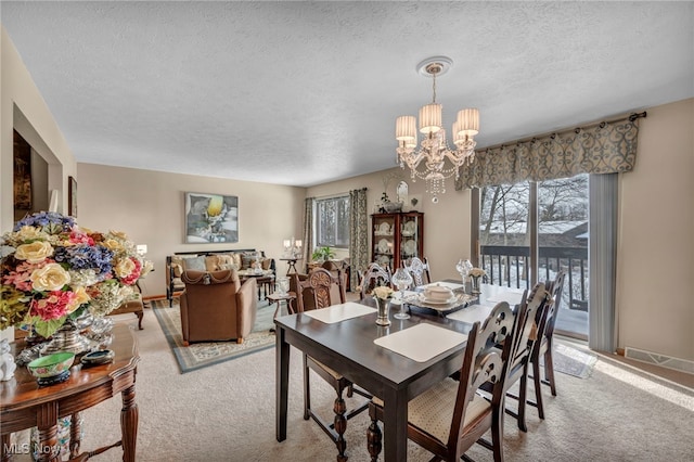 dining area featuring light carpet, a notable chandelier, and a textured ceiling