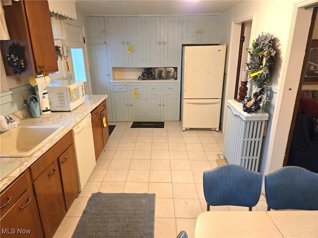 kitchen with sink, white appliances, and light tile patterned floors