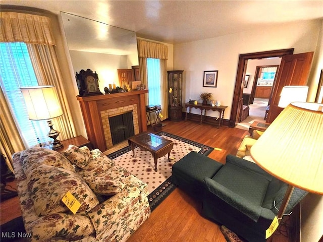 living room featuring hardwood / wood-style flooring, a brick fireplace, and plenty of natural light