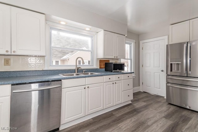 kitchen with dark hardwood / wood-style floors, sink, backsplash, white cabinets, and stainless steel appliances