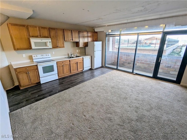 kitchen featuring sink, white appliances, expansive windows, and dark colored carpet