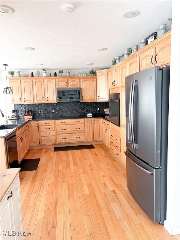 kitchen featuring light brown cabinetry, sink, decorative light fixtures, light hardwood / wood-style flooring, and black appliances