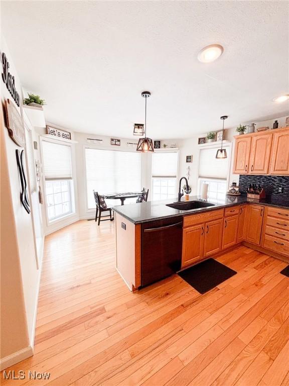 kitchen with sink, dishwasher, hanging light fixtures, backsplash, and light hardwood / wood-style floors