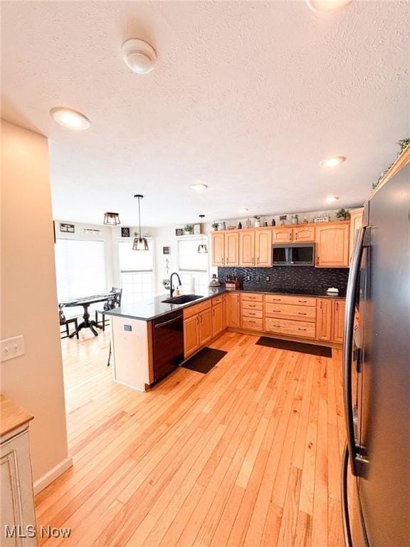 kitchen featuring appliances with stainless steel finishes, light hardwood / wood-style flooring, kitchen peninsula, and decorative light fixtures