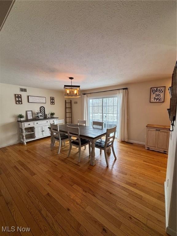 dining space with light hardwood / wood-style flooring and a textured ceiling