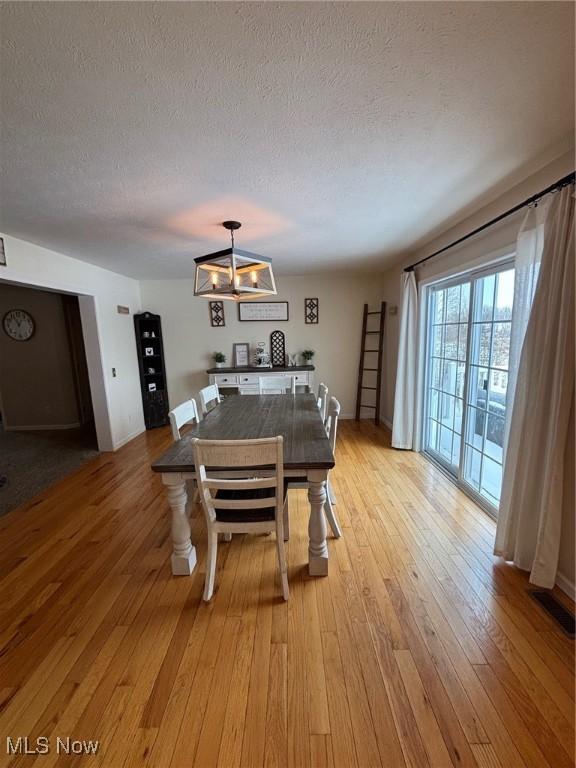 dining space with light hardwood / wood-style floors and a textured ceiling