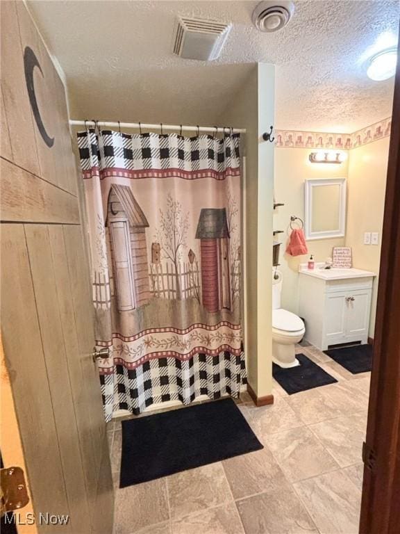 bathroom with a shower with curtain, vanity, a textured ceiling, and toilet