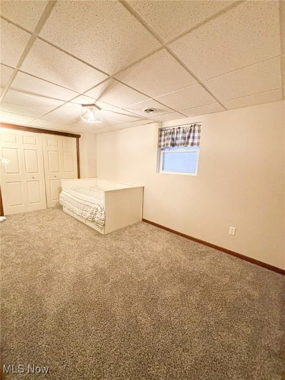 unfurnished bedroom with carpet flooring, a closet, and a drop ceiling