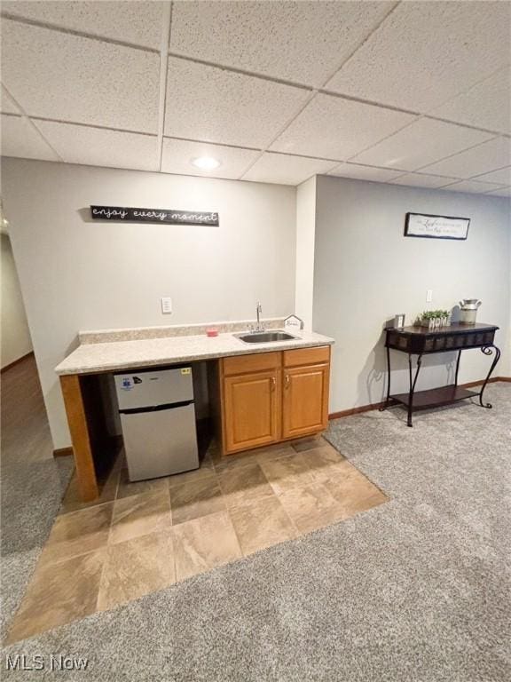 bar featuring a drop ceiling, sink, fridge, and light colored carpet