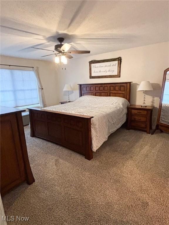 carpeted bedroom featuring ceiling fan and a textured ceiling