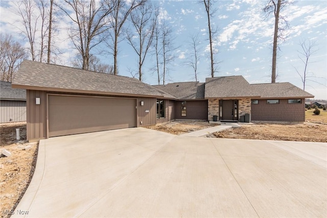 view of front of property featuring roof with shingles, concrete driveway, and an attached garage