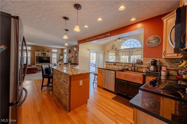 kitchen with appliances with stainless steel finishes, a center island, sink, and light hardwood / wood-style flooring