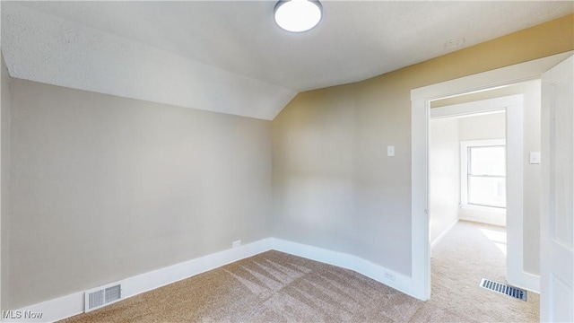 additional living space with vaulted ceiling and light carpet