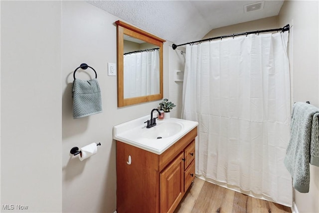 bathroom featuring vanity, lofted ceiling, hardwood / wood-style floors, and curtained shower