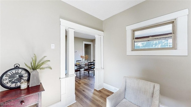 hallway with light hardwood / wood-style flooring and decorative columns