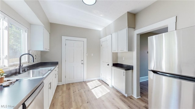 kitchen featuring appliances with stainless steel finishes, sink, white cabinets, and light wood-type flooring