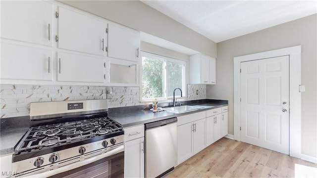 kitchen featuring sink, appliances with stainless steel finishes, backsplash, light hardwood / wood-style floors, and white cabinets