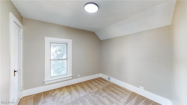 additional living space featuring vaulted ceiling and carpet flooring