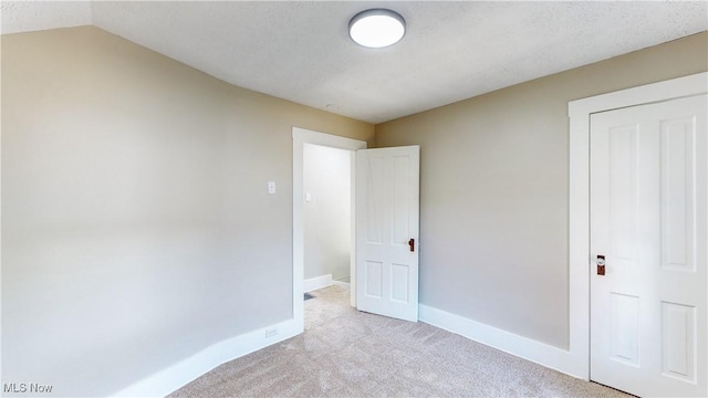 unfurnished bedroom with light colored carpet and a textured ceiling