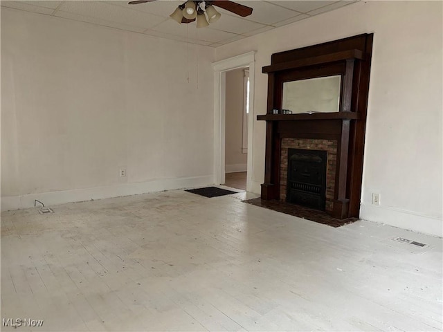 unfurnished living room with a fireplace, a paneled ceiling, and ceiling fan