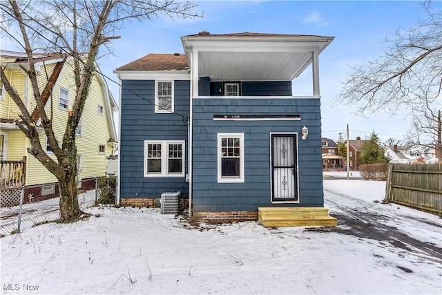 snow covered back of property with central AC