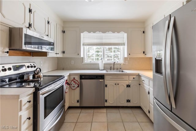 kitchen featuring appliances with stainless steel finishes, tasteful backsplash, sink, white cabinets, and light tile patterned floors