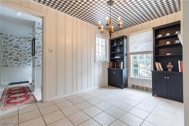 unfurnished dining area with light tile patterned floors, a chandelier, and built in shelves