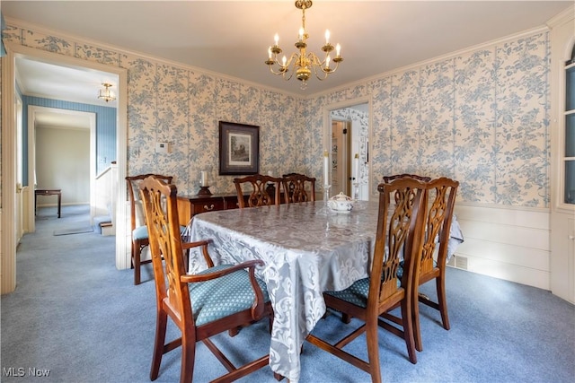 dining space with crown molding, carpet flooring, and an inviting chandelier