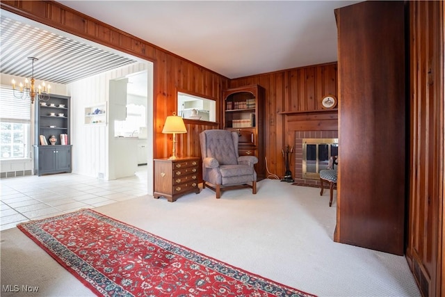 living area with an inviting chandelier, a fireplace, light colored carpet, and wood walls