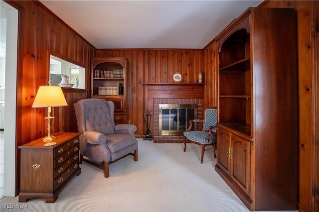 sitting room featuring light carpet, a brick fireplace, and wood walls