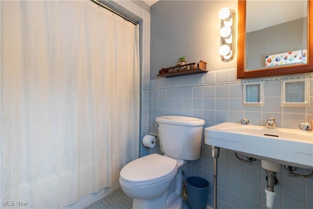 bathroom with toilet, tile patterned flooring, and tile walls