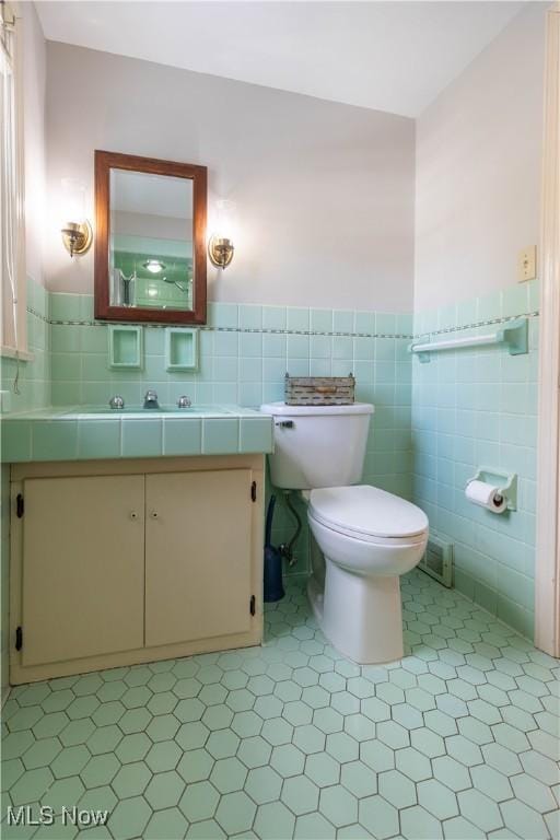 bathroom with vanity, toilet, and tile walls