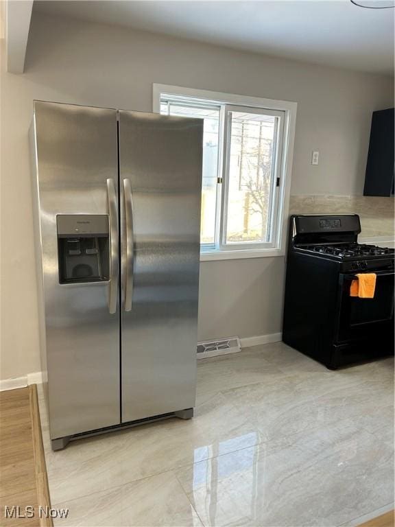 kitchen featuring gas stove and stainless steel fridge with ice dispenser