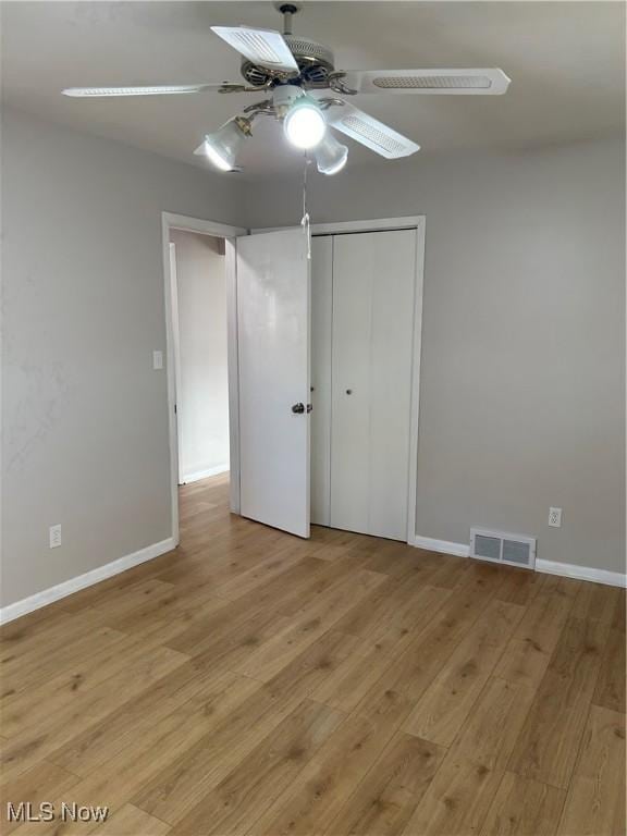 unfurnished bedroom with ceiling fan, a closet, and light hardwood / wood-style flooring