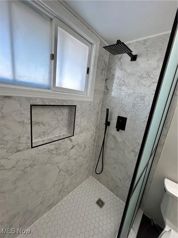 bathroom featuring tiled shower and toilet