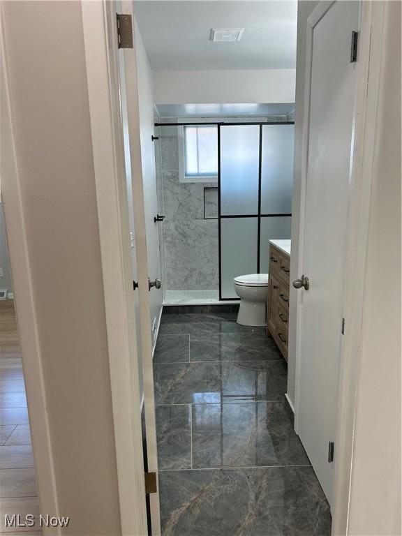 bathroom featuring vanity, toilet, and walk in shower