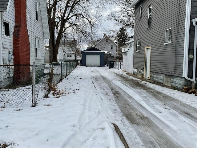 yard layered in snow featuring an outbuilding and a garage