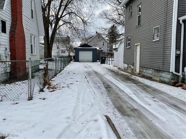 yard layered in snow with an outbuilding and a garage