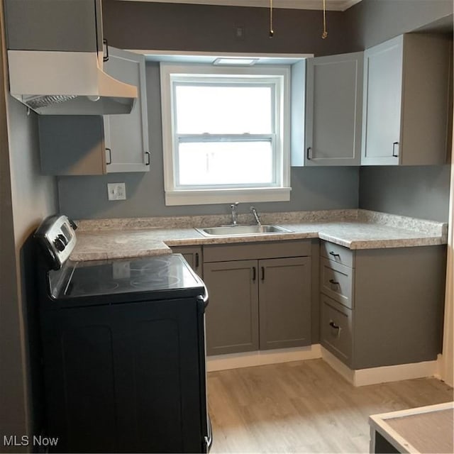 kitchen with stove, sink, gray cabinetry, and light hardwood / wood-style floors