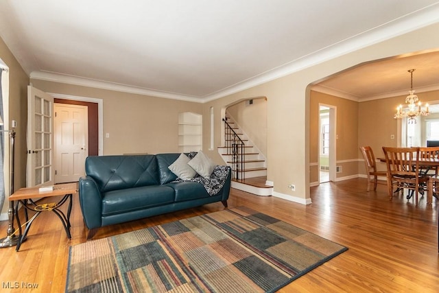 living room featuring an inviting chandelier, crown molding, and hardwood / wood-style floors