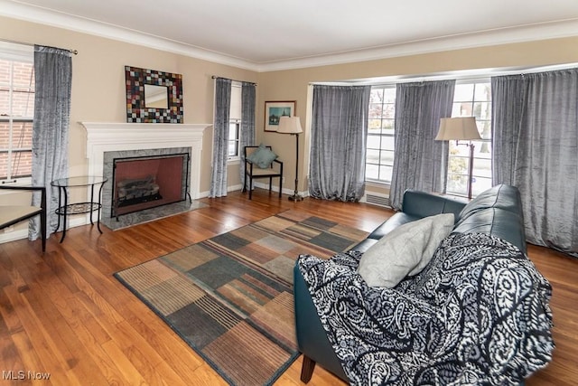 living room featuring hardwood / wood-style flooring, ornamental molding, a high end fireplace, and a wealth of natural light