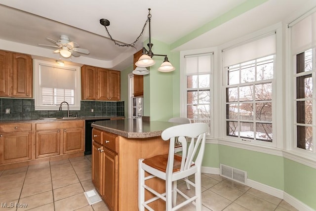 kitchen with a kitchen island, tasteful backsplash, black dishwasher, sink, and hanging light fixtures