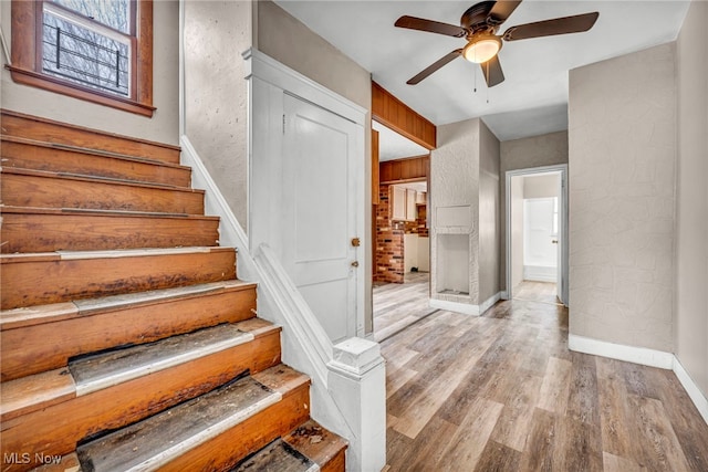 staircase with hardwood / wood-style flooring and ceiling fan