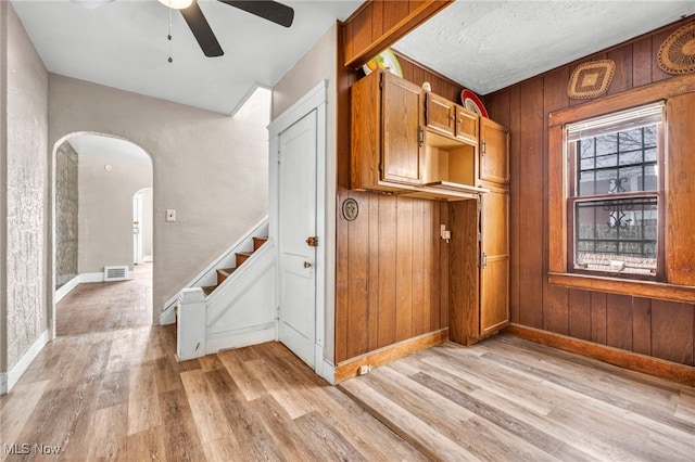 interior space with ceiling fan, hardwood / wood-style floors, and wood walls