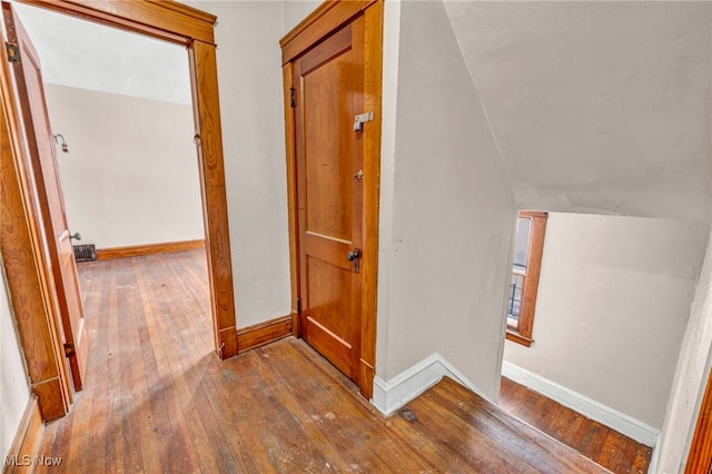 corridor with hardwood / wood-style flooring and lofted ceiling