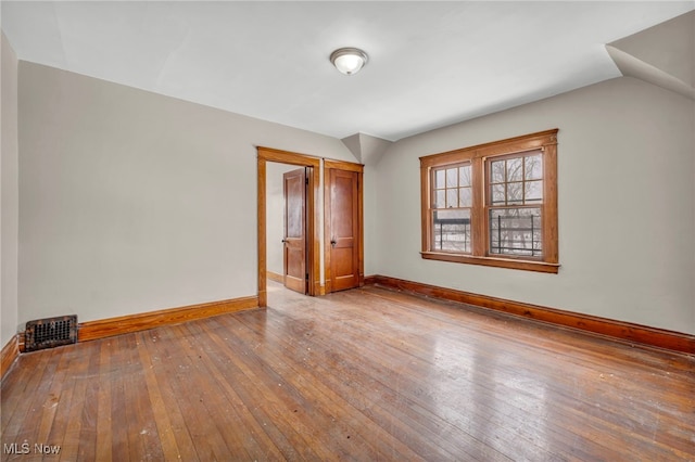 unfurnished bedroom featuring hardwood / wood-style flooring and vaulted ceiling