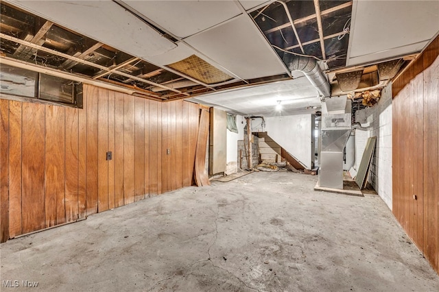 basement featuring heating unit and wood walls