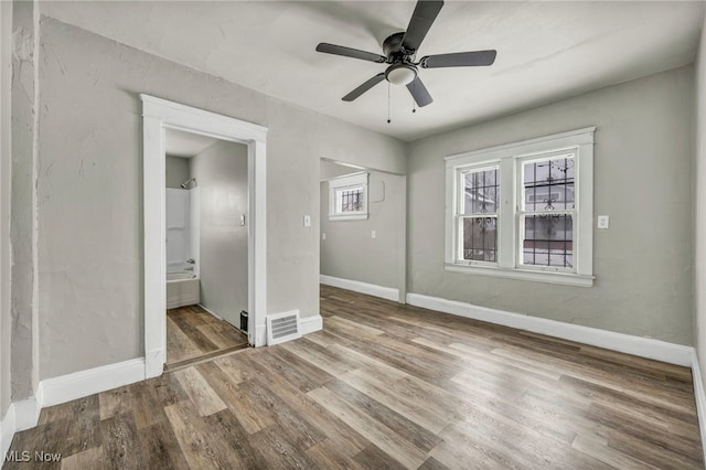 unfurnished bedroom with connected bathroom, hardwood / wood-style flooring, a closet, and ceiling fan