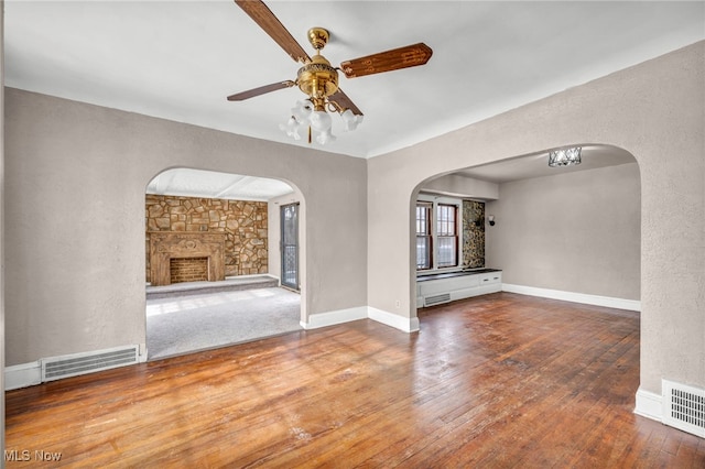 empty room featuring ceiling fan, a fireplace, and hardwood / wood-style floors